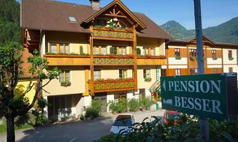 A charming building with traditional architecture in a quiet setting. In front of the house stands a sign that reads "PENSION BESSER".