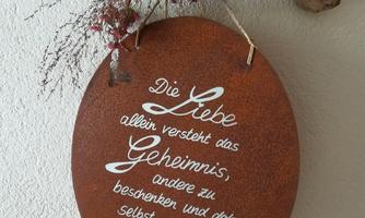 A creative metal sign with a message about love. It is decorated with dried flowers and a piece of wood.