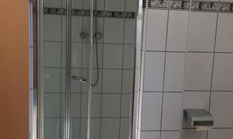 A modern shower in a bathroom. The walls are tiled and there is an elegant showerhead.