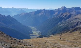 An impressive mountain landscape with expansive valleys and high peaks. The clear sky and natural beauty invite exploration.