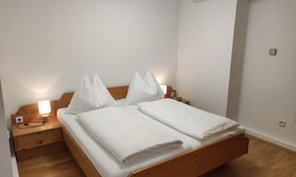 A cozy bedroom with a large bed and two nightstands. The walls are light and the decor is simple and modern.