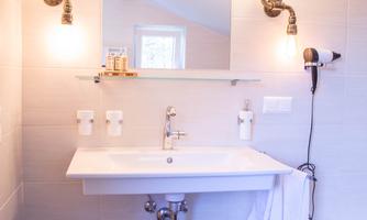 A modern bathroom with a sink and a mirror. The walls are tiled in light colors, and warm light sources create an inviting atmosphere.