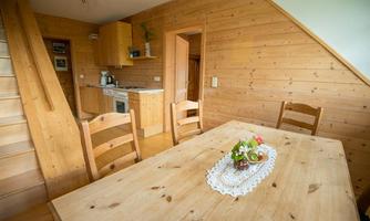 A cozy wooden kitchen with a dining table and chairs. The room is brightly and friendly decorated.
