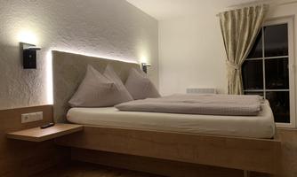 A modern bedroom with a large, comfortable bed and soft lighting. A window with curtains provides additional light and a cozy atmosphere.