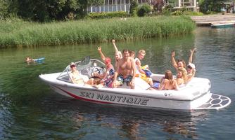A group of people is sitting on a motorized boat on clear waters. It is sunny and they seem to be having fun.