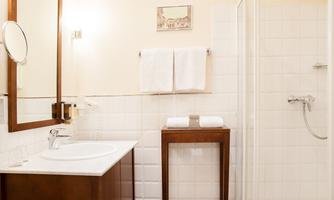 A modern bathroom with a shower and a sink. White walls and wood accents create an inviting atmosphere.