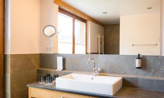 A modern bathroom with an elegant sink made of white ceramic. Large windows provide plenty of natural light and a pleasant atmosphere.