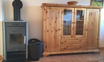 A cozy living space with a modern fireplace and a wooden cabinet. The room is bright and friendly with a beautiful wooden floor.