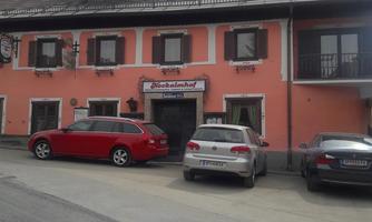 A pink building with a restaurant in the foreground. Several cars are parked in front of the house.