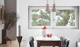 A modern dining room with a wooden table and black chairs. Large windows let in plenty of daylight.