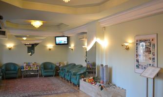 An inviting entrance area with comfortable green armchairs. A television and a decorative picture hang on the wall.
