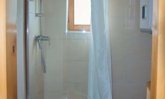 A modern bathroom with a shower and a white shower curtain. A window lets in natural light and creates a bright atmosphere.