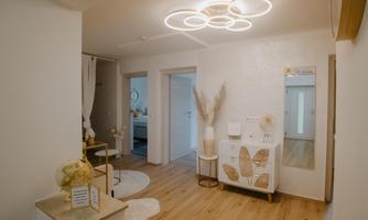 A bright hallway with modern design and warm wooden flooring. There is a mirror on the wall and a decorative dresser.