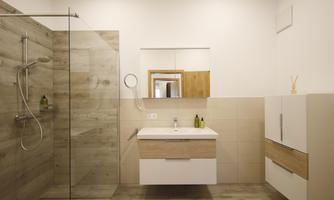 A modern bathroom with a spacious glass shower. The bright room features an elegant vanity combination and large mirrors.