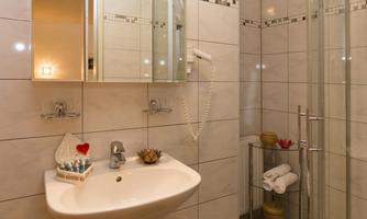 A modern bathroom with a shower and a sink. It is bright and well-organized, with decorative elements.