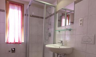 A modern bathroom with a shower and a sink. The walls are tiled and a red curtain creates a cozy atmosphere.