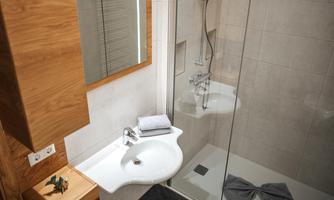 A modern bathroom with a shower and a sink. The walls are brightly tiled and there are wood elements.