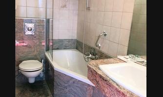 A modern bathroom with a bathtub and a shower. The floor and the walls are clad in gray marble.