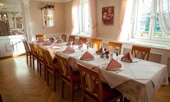 An elegant dining room with a long table set for a meal. The tables are adorned with cutlery, napkins, and flowers.