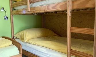 A simple room with a bunk bed and a single bed. The walls are bright green, and the bedding is yellow.