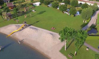 A beautiful beach area with a slide and plenty of greenery. In the background, there are some tents and trees visible.