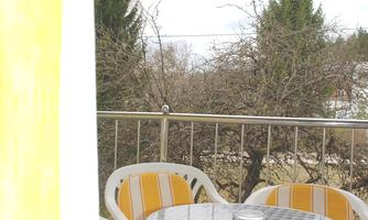 A small outdoor area with a round table and four chairs with yellow and white stripes. In the background, there are bare trees and a gray sky.