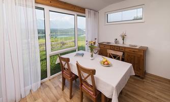 A bright dining area with a table and chairs. Large windows provide a beautiful view of the landscape.
