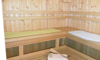 A cozy wooden sauna with two benches. On the floor lies a towel and a small boat.