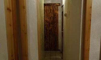 A narrow hallway with an arched door opening. Light colors and wood paneling can be seen on the walls.