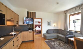 A modern holiday apartment with a kitchenette and a cozy seating area. Large windows provide bright light and an inviting atmosphere.