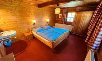 A cozy bedroom with wooden walls and a large bed. The room is simply furnished and has a warm, inviting atmosphere.