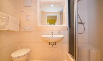 A modern bathroom with a shower, a sink, and a toilet. The walls are bright and attractively designed.