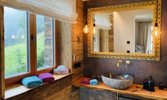 A modern bathroom with wooden paneling and a large mirror. Colorful towels are lying on the windowsill, creating a cozy atmosphere.