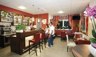 A modern restaurant with a stylish bar and comfortable seating. The decor is friendly and inviting, with plants and decorations.