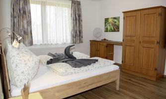 A cozy bedroom with a wooden bed and fresh bedcovers. The room design is modern with soft colors and natural light.