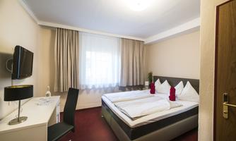 A cozy hotel room with a double bed and fresh linens. A desk and a television are also available.