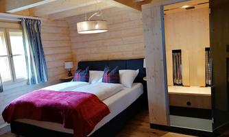 A cozy bedroom with a large bed and modern wooden details. A walk-in closet is located next to the bed.