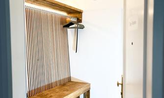 A bright room with a wooden bench and decorative pendant lights. The wall is designed with vertical wooden slats.