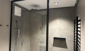 A modern shower with glass partition and gray tiles. It offers an elegant and bright atmosphere.