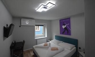 A modern room with a large double bed and colorful wall decoration. There is a television and a small desk.