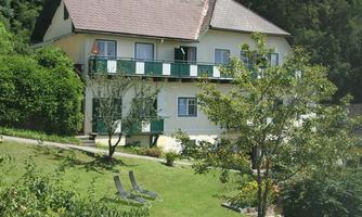 A charming house with a balcony and a green meadow. Surrounded by trees and deck chairs, it is an ideal place to relax.