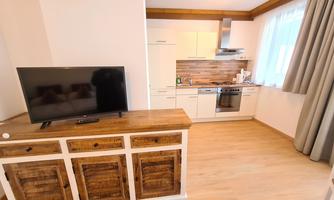Modern kitchen with wooden details and a television.  

Bright, inviting atmosphere and large windows.