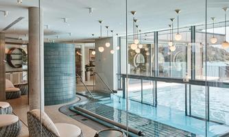 A modern spa with a relaxing pool and cozy seating areas. The large window front provides plenty of daylight and a view of the outdoors.