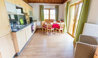 A bright kitchen with wooden ceilings and modern appliances. A cozy dining area with a round table and a view of the outdoor area.