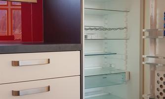 A modern refrigerator with an empty interior. The kitchen furnishings are simple and functional.