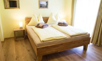 A cozy bedroom with a double bed and wooden furniture. Soft colors and plenty of natural light create an inviting atmosphere.