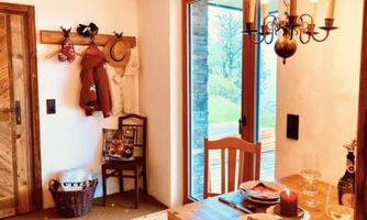 A cozy dining area in a chalet with wood decor. Large windows offer a view of the greenery.