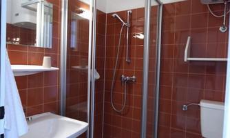 A modern bathroom with a shower and a sink. The walls are in a warm red tone.