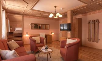 A cozy living room with red sofas and a coffee table. The room is bright and modernly furnished, with a television and wooden details.