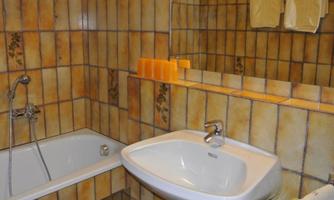 A bathroom with a bathtub and a sink. The walls are decorated with brown tiles.